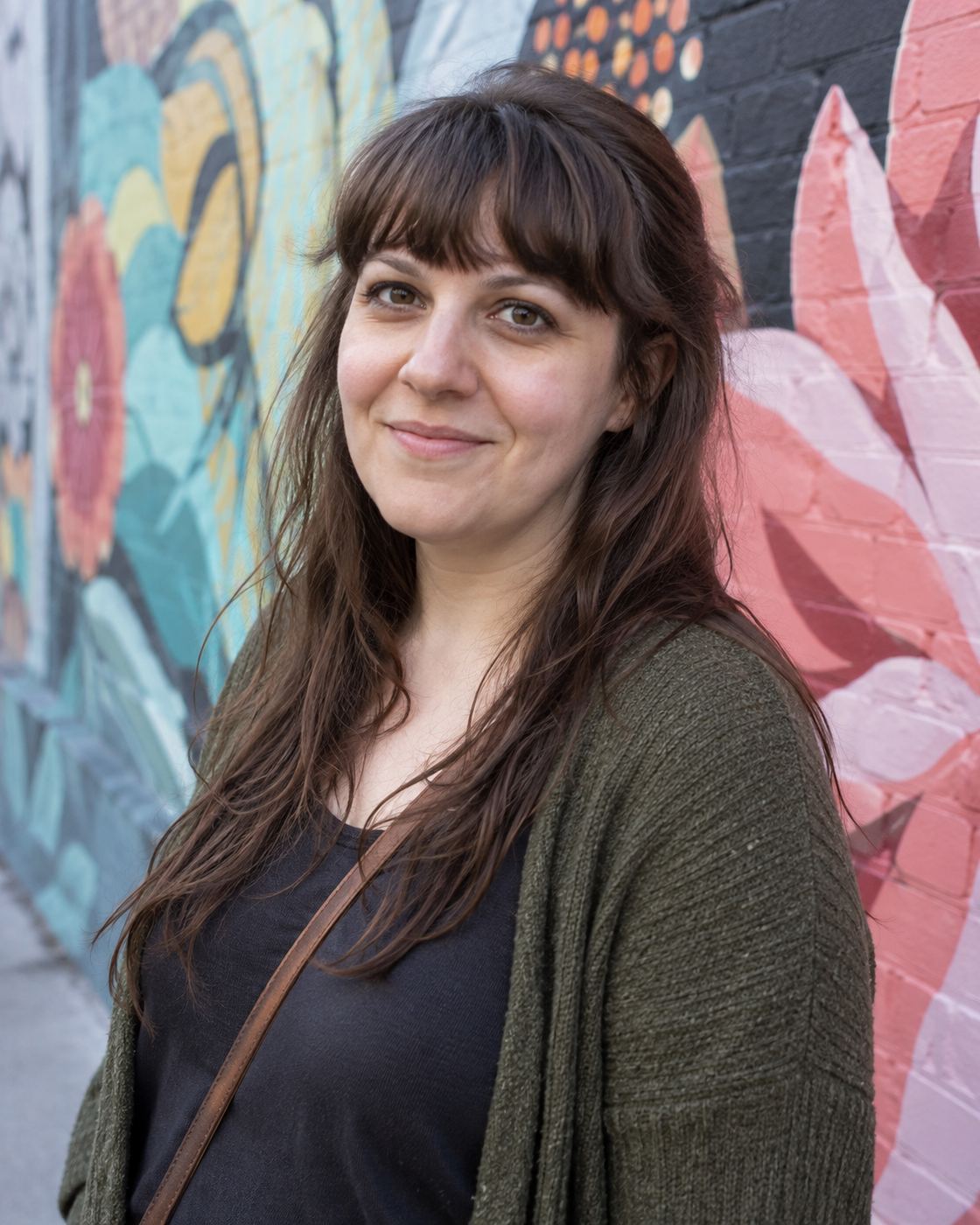 Illustrative portrait of a woman in a green cardigan beside a colorful mural